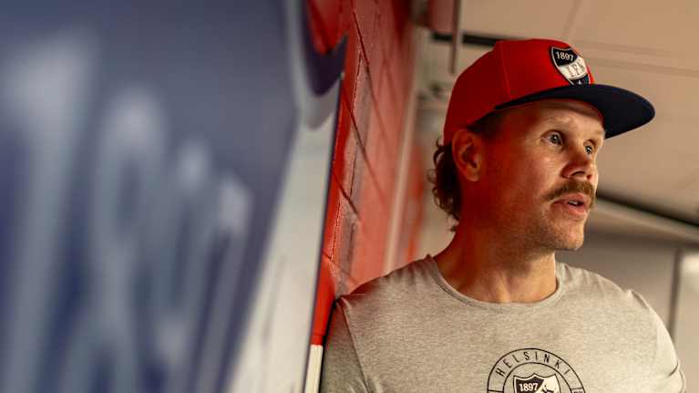 HIFK:n päävalmentaja Olli Jokinen poseeraa HIFK-logon edessä.
