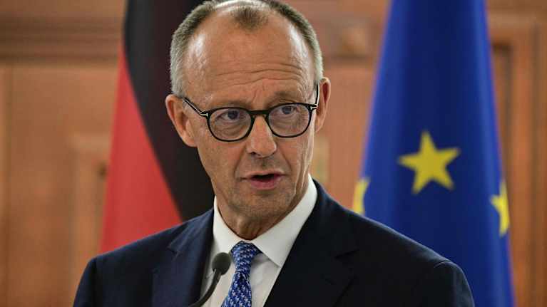 Saksan liittokansleri Friedrich Merz puhumassa lehdistötilaisuudessa, taustalla näkyvät Saksan ja EU:n liput.