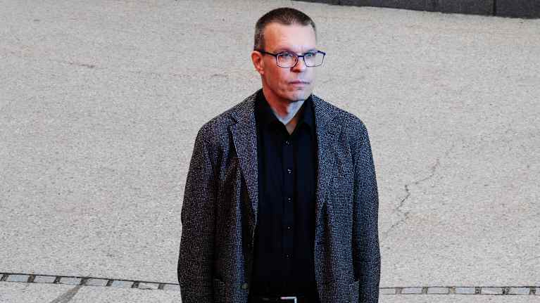 Professori Samuel Kaski poseeraa kameralle Otaniemessä. Kasken kasvoille osuu punainen valo.