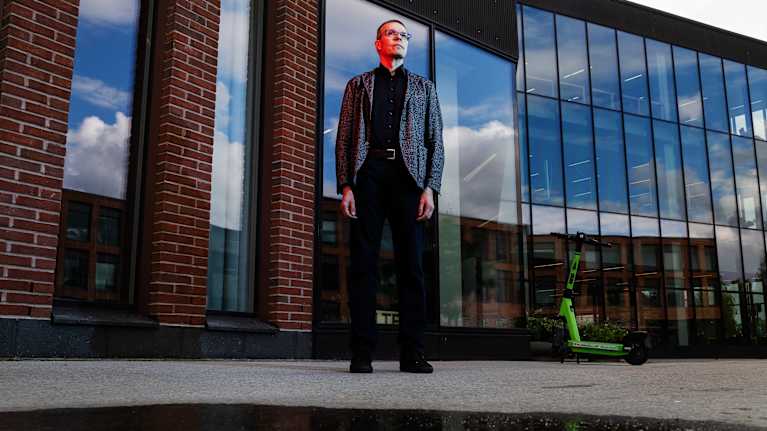 Professori Samuel Kaski poseeraa kameralle Otaniemessä. Kasken kasvoille osuu punainen valo.