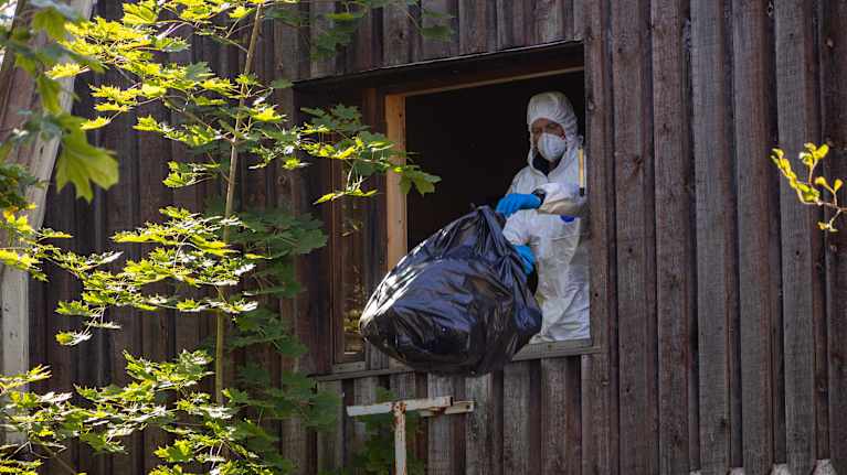 Viranomainen heittämässä jätesäkkiä ulos ikkunasta Kouvolan Voikkaalla.