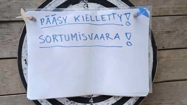 Tikkataulu, johon on kiinnitetty kahdella tikalla paperi, jossa lukee käsin kirjoitettuna "Pääsy kielletty! Sortumisvaara!"