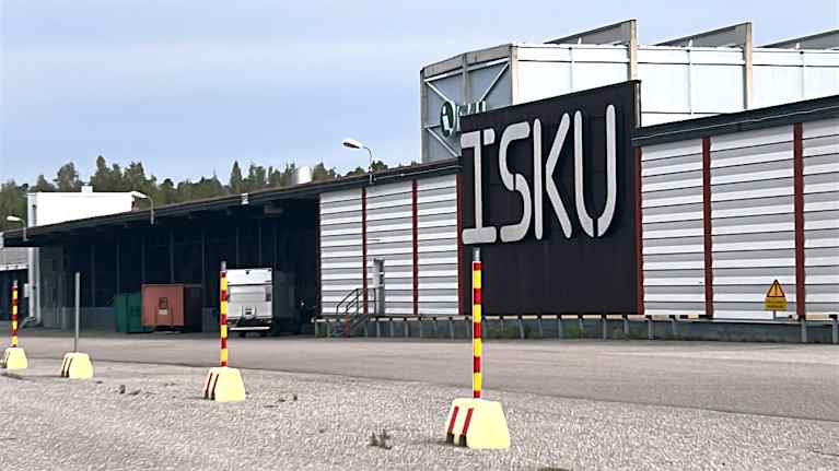 Lähikuvassa on matala ja suuri harmaa teollisuusrakennus. Julkisivussa lulee suurin kirjaimin ISKU. 
