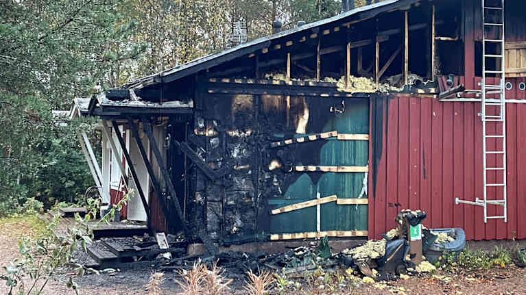 Punaisen rivitalon pääty, josta  puolet on palanut mustaksi. Yläpohjan lautoja on revitty irti.