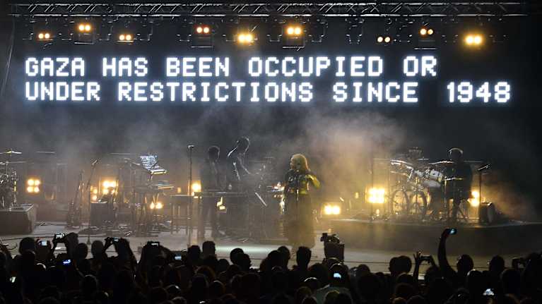 Massive attack lavalla ja taustalla poliittinen viesti "Gaza has been occupied or under restrictions since 1948".