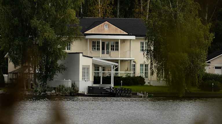 Suuri Vaalea talo järven rannalla.