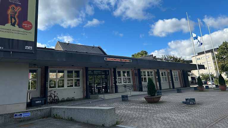 Hämeenlinnan teatterin rakennus ja lippu puolitangossa. 