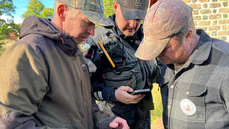 Projektipäällikkö Mikko Toivola, koiranohjaaja Nestori Heinonen ja toiminnanohjaaja Tommy Arfman katsovat drooninkuvaa Kemiönsaaressa.