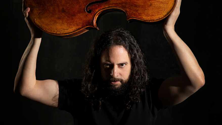 Mies pitää viola da gambaa päänsä päällä käsiensä varassa.