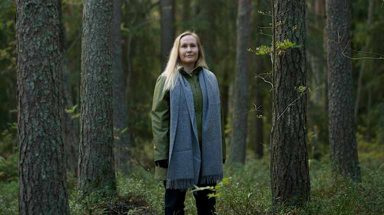 Tutkijatohtori Kaisa Lehosmaa seisoo puiden välissä.