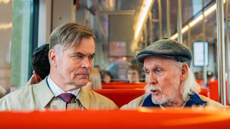 Kaksi miestä istuu metron penkeillä.