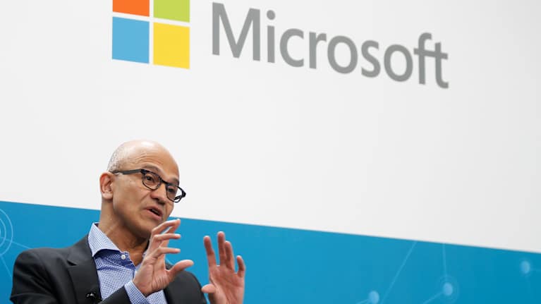I förgrunden vd Satya Nadella, och upptill Microsofts logo.