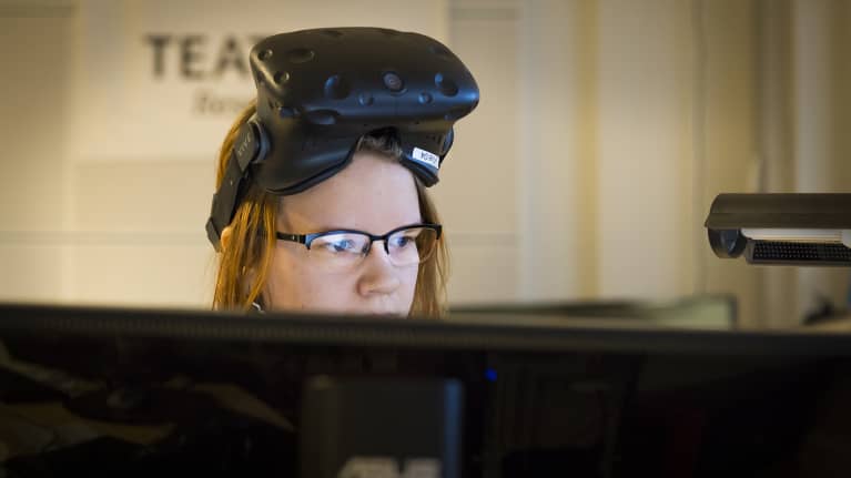 Naine virtuaalilasit otsalla tietokoneen ääressä.