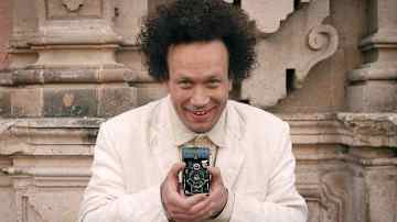 Mies katsoo kameraan kamera kädessä