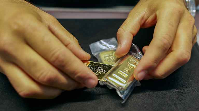 Kultaharkkoja kultakauppiaan käsissä.