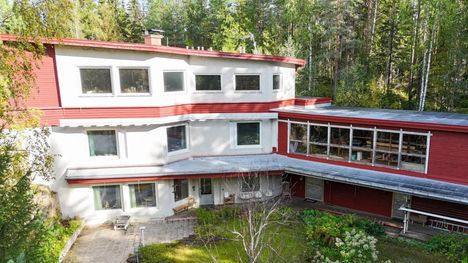 Talon takapiha. Talossa on asuinkerroksia sekä punaisessa osassa suuri puuverstas, jossa on isot ikkunat. Valkoinen osa on upotettu kallioon.