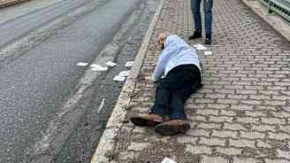 Ben Zyskowicz makaa kadulla, avustaja ottaa kuvaa kännykällä.