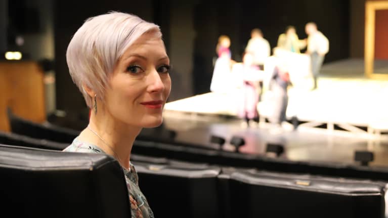 Kirjailija Merja Mäki istuu katsomossa Seinäjoen kaupunginteatterissa ja katsoo kameraan.