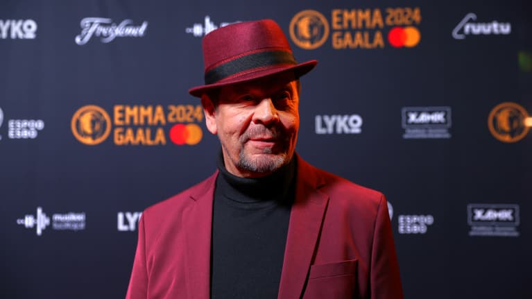 Pate Mustajärvi violetissa puvussa ja hatussa.