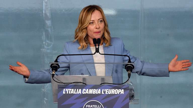 Italian pääministeri Giorgia Meloni puhujapöntössä kädet levällään.