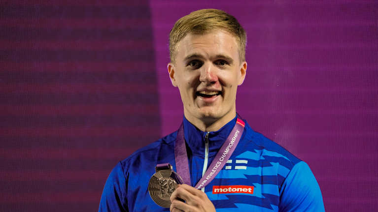 Helander hymyilee mitalin kanssa.