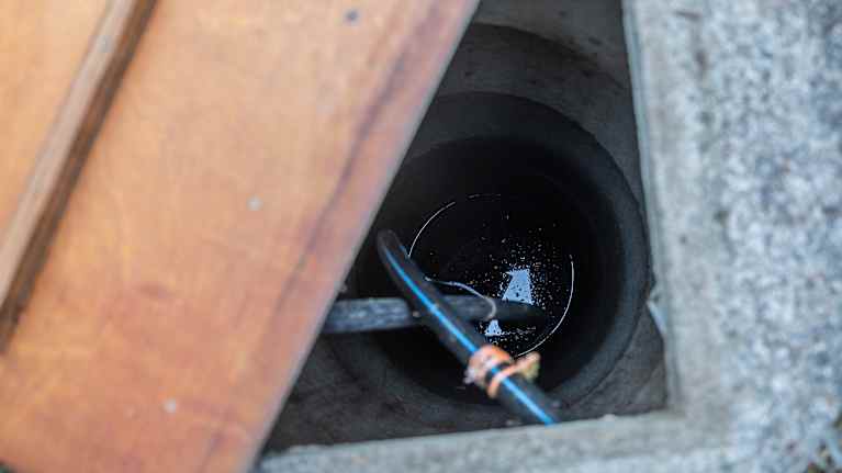 Rengaskaivo, jonka kansi on raollaan. Veden pinta siintää usean metrin syvyydessä.