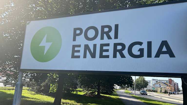 Pyörätien vieressä on kyltti, jossa lukee Pori energia. Kuva on alkusyksyllä otettu, ruoho vihertää.