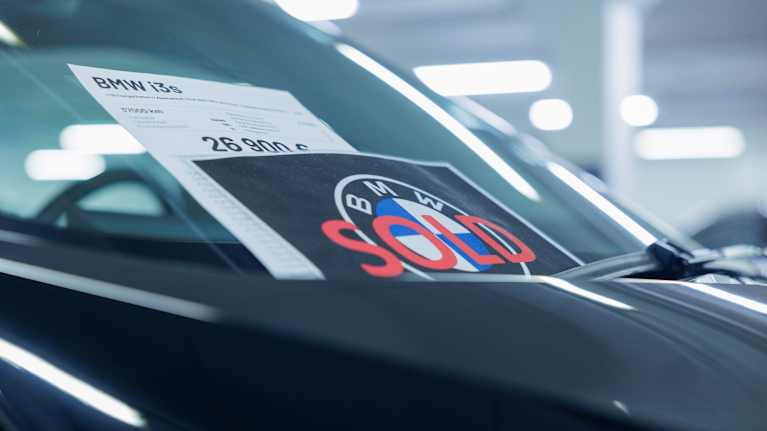 Tumman auton tuulilassissa on kyltti kertomassa että se on myyty.