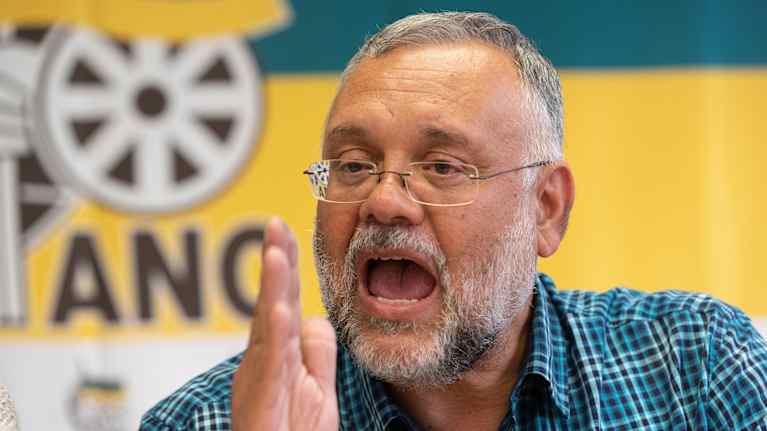 Ebrahim Rasool puhuu ANC:n lipun edessä.