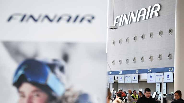 Ihmisiä ja Finnairin logoja lentoasemalla.