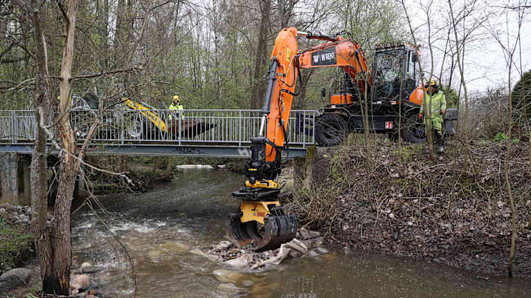 Kaivuri raivaa kivia pois joesta.