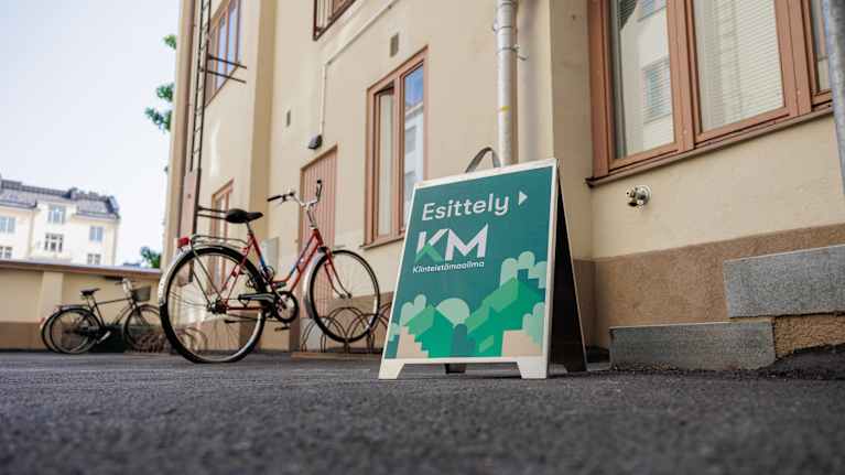 Asuintalon edustalla on asuntoesittelyn kyltti.