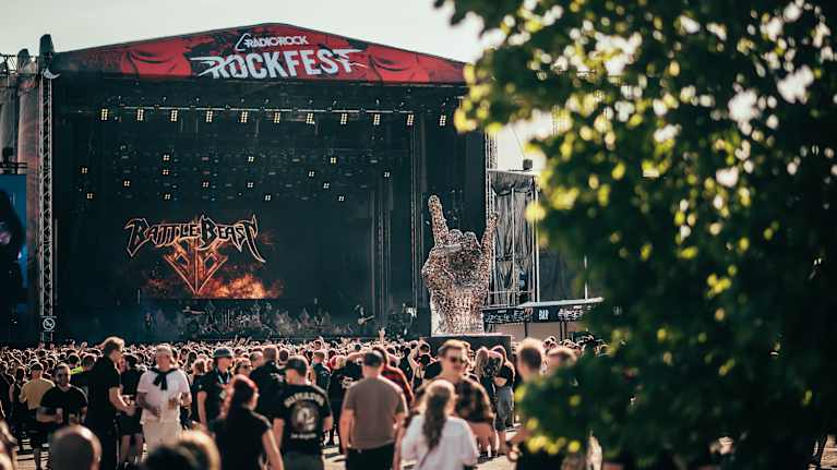 Ihmisiä kulkee festariyleisössä. Takana näkyy iso lava.