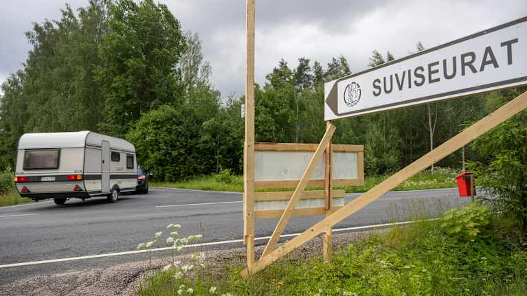 suviseurat kyltti ja autoja asuntovanut perässä.