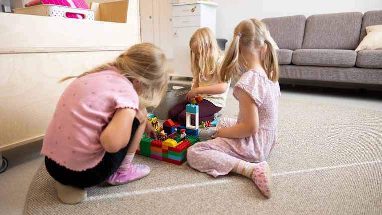 Tytöt rakentavat Lego-palikoilla päiväkodin lattialla.