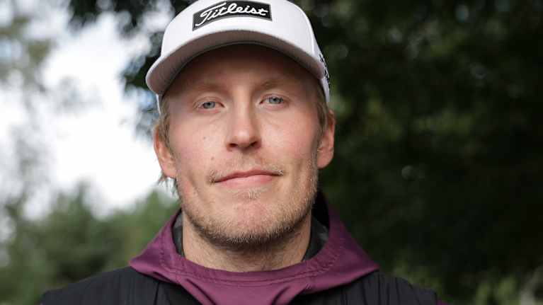 Henkilö kuvassa on pukeutunut lämpimästi ulkoiluun ja hänellä on lippalakki, tumma toppaliivi ja huppari.