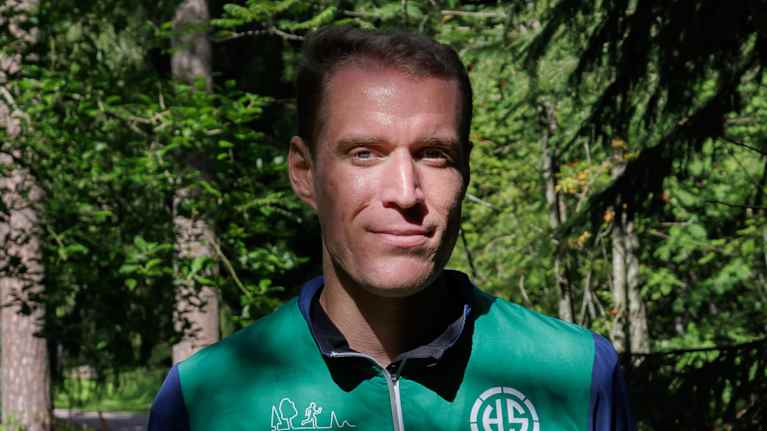 Suunnistaja Tuomas Heikkilä katsoo kameraan metsän keskellä.