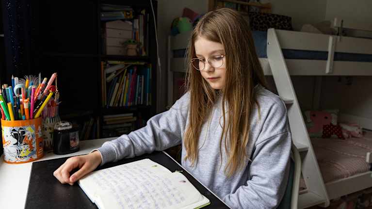 Sara Viiman lukee läksyjä kotona koulupöytänsä ääressä.