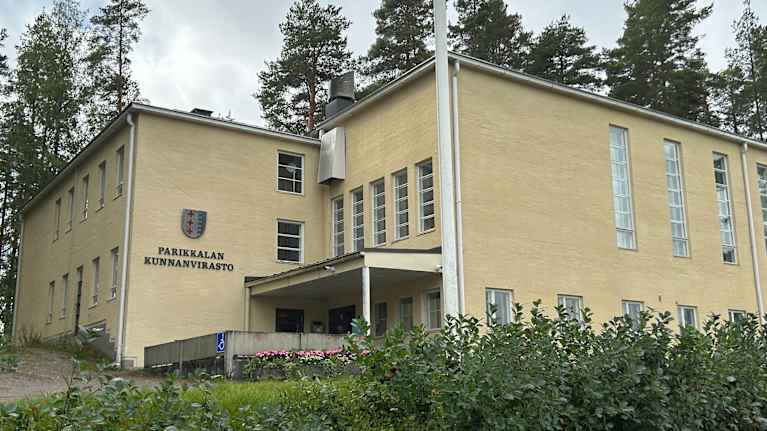 Parikkalan kunnantalon etupiha ja sisäänkäynti. Kunnan vaakuna on näkyvissä rakennuksen seinällä.