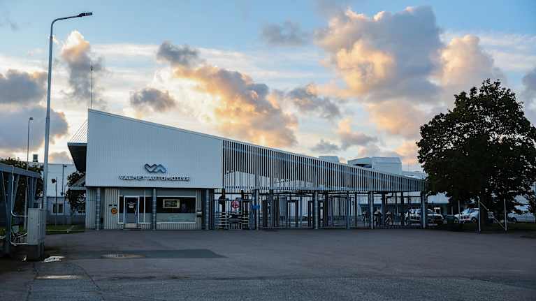 Uudenkaupungin autotehtaan pääportti. Valkoinen rakennus, aitaa.