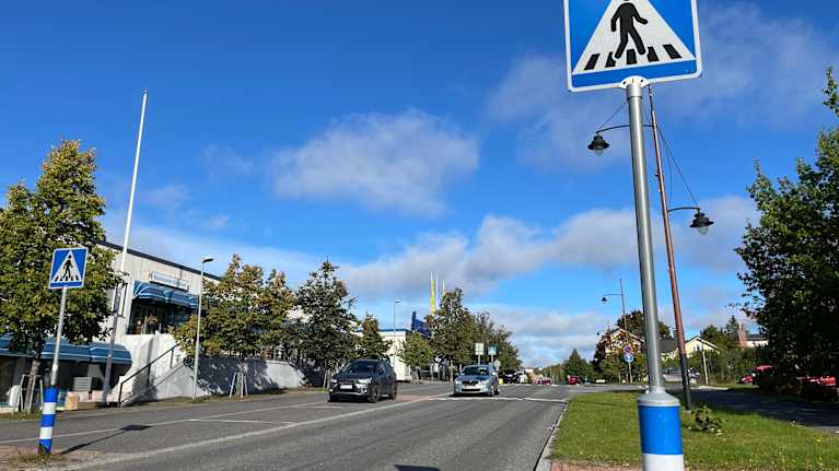 Kuhmoisten keskustan liikennettä ja rakennuksia, etualalla suojatien liikennemerkki.