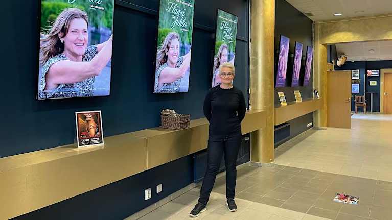 Savon Kinot elokuvateatteriketjun teatteripäällikkö Sari Peltonen seisoo aulatiloissa elokuvajulisteiden edessä.