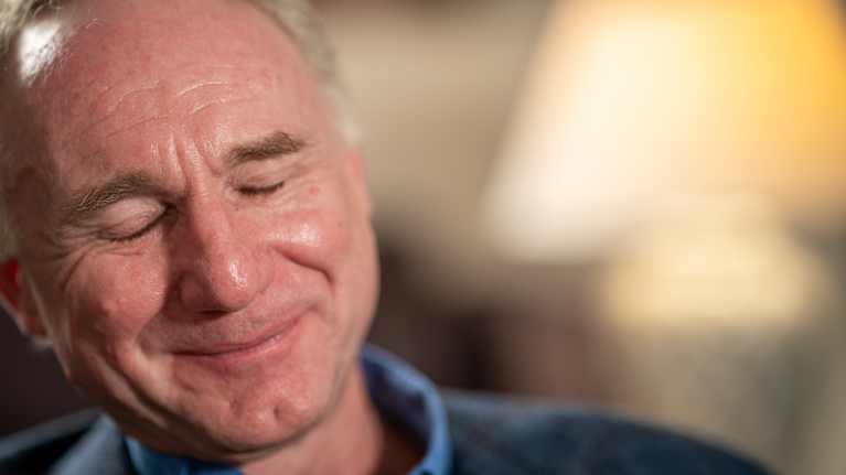 Kirjailija Dan Brown hymyilee silmät kiinni lähikuvassa.