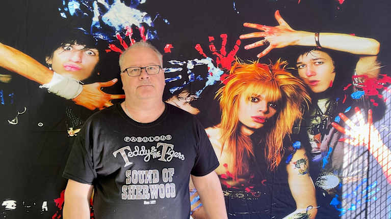 Jarmo Tanskanen ison Hanoi Rocks -bändilakanan edessä.