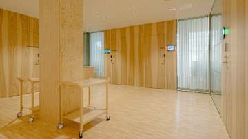 Tila, jossa on puupanelointia seinissä ja lattioissa, ja se on valaistu pehmeällä, luonnonvaloa jäljittelevällä valolla. 