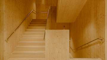 Moderni sisätila, jossa nähdään vaaleasta puusta tehdyt portaat ja seinät.