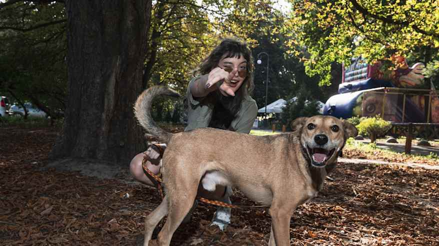 Marta kyykistyneenä iloisen koiran taakse. Molemmat hymyilee iloisesti ja katsoo kameraan.
