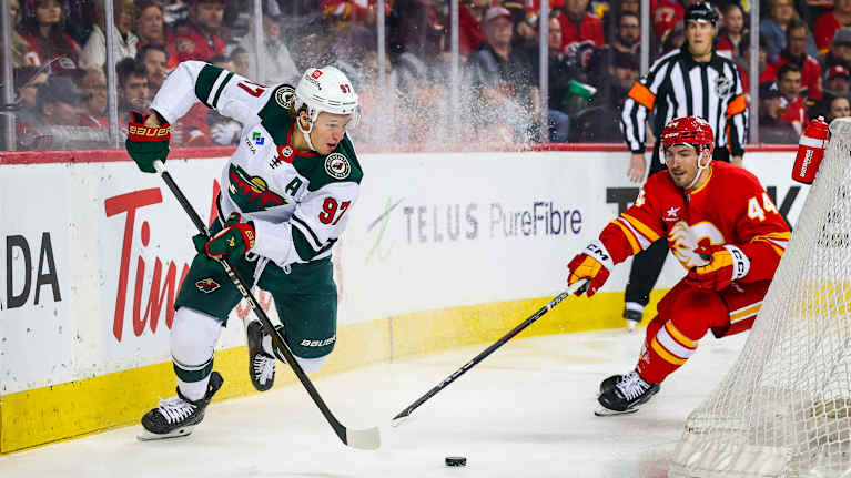 Kirill Kaprizov yrittää karata Calgary Flamesin puolustajalta Joel Hanleylta.