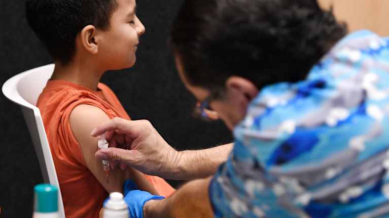 Nuori poika saa rokotuksen olkapäähän. 