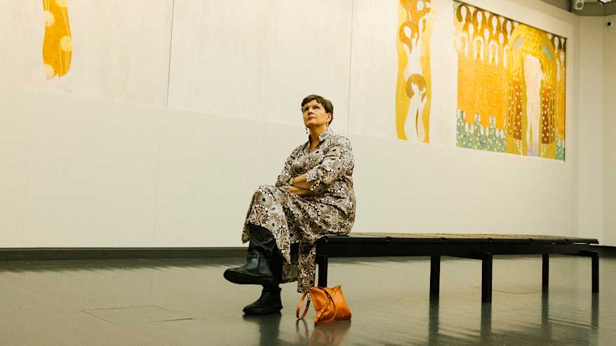 Nainen istuu penkillä taidemuseossa Gustav Klimtin teoksen edessä.